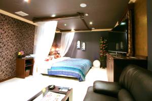 um quarto com uma cama, uma televisão e um sofá em SARI Seki Inter (Adult Only) em Kameyama