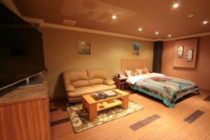 a bedroom with a bed and a couch and a table at SARI Seki Inter (Adult Only) in Kameyama