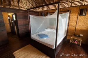 Cette chambre comprend un lit à baldaquin. dans l'établissement Rimba Resort - Dive Centre & Spa, à Pulau Sibu