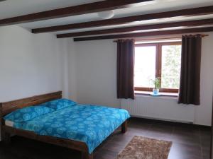 a bedroom with a blue bed and a window at penzionMoravia in Moravská Nová Ves