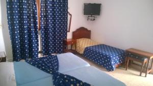 Cette chambre comprend 2 lits, une télévision et des rideaux. dans l'établissement Hotel Excellence, à Tunis