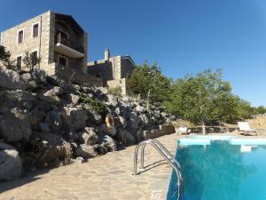 a swimming pool in front of a rock wall at Arodamos Guesthouse in Krousón
