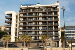 a tall building with palm trees in front of it at Apartamentos Fuengirola Playa in Fuengirola