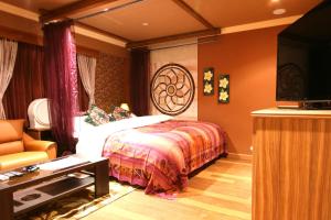 a bedroom with a bed and a tv and a couch at AURA Seki Inter (Adult Only) in Kameyama
