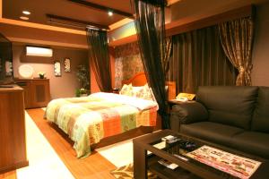 a bedroom with a bed and a couch at AURA Seki Inter (Adult Only) in Kameyama