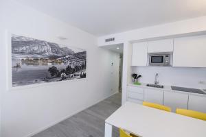 una cocina con armarios blancos y una pintura en la pared en Bertamini Apartments, en Nago-Torbole