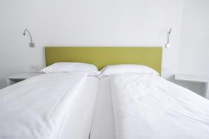 a bed with white sheets and a green headboard at Bertamini Apartments in Nago-Torbole