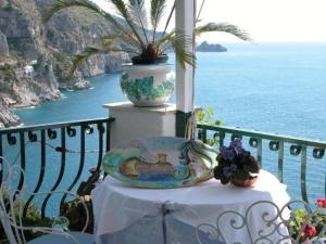 a table with a plate and a vase on a balcony at Hotel La Perla in Praiano +37 photos