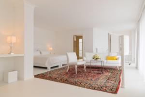 a white bedroom with a bed and a couch and a table at Hotel Villa Seeschau - Adults only in Meersburg