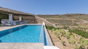 a swimming pool in front of a house at Mykonos Panormos Villas in Mykonos