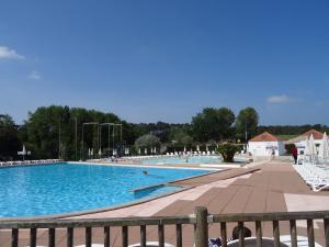 a large swimming pool with white chairs and people in it at Studio avec vue sur Lac in Talmont