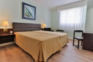 a bedroom with a bed and a table and chairs at Hotel Apartamento Solverde in Espinho