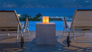 two chairs with a candle on a table in front of a pool at Mykonos Panormos Villas in Mykonos