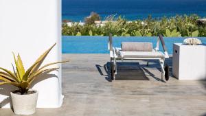 a white chair sitting on a patio next to a plant at Mykonos Panormos Villas in Mykonos