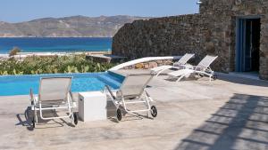 a group of chairs sitting next to a swimming pool at Mykonos Panormos Villas in Mykonos