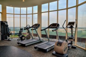 a gym with cardio equipment in a building with windows at Holi Afiniti Themed Suites in Nusajaya