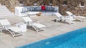a group of chairs and a couch next to a pool at Mykonos Panormos Villas in Mykonos