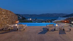 a group of chairs sitting next to a swimming pool at Mykonos Panormos Villas in Mykonos