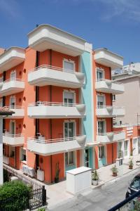 ein orangefarbenes Gebäude mit weißen Balkonen auf einer Straße in der Unterkunft Residence Olimpo in Rimini