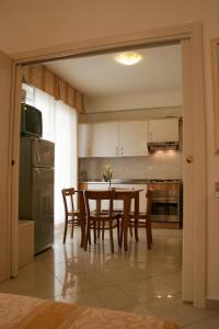 eine Küche mit einem Tisch und Stühlen sowie einem Kühlschrank in der Unterkunft Residence Olimpo in Rimini