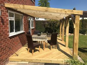 a wooden pergola with a table and chairs on a deck at HP Bed and Breakfast in Congleton