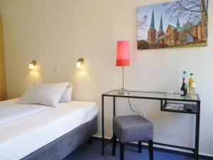 a bedroom with a bed and a desk with a lamp at Hotel Am Mühlenteich in Lübeck