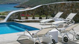 a row of chairs next to a swimming pool at Mykonos Panormos Villas in Mykonos
