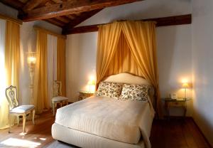 a bedroom with a bed with a canopy and two chairs at Villa Foscarini Cornaro in Gorgo al Monticano