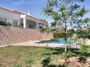 a house with a stone wall and a tree at Villa Casa do Monte in Silves