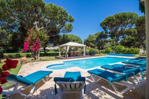 a pool with lounge chairs and a gazebo at Villa Popa in Quarteira