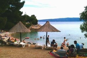 a group of people sitting on a beach at Turković Apartments in Žgaljić