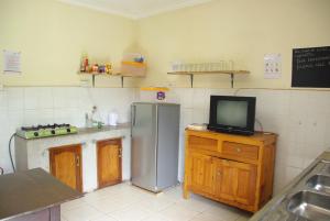 a kitchen with a refrigerator and a tv on a counter at Bikeventures House Uganda in Jinja