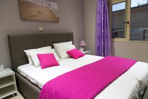 1 dormitorio con 1 cama grande con almohadas rosas en Litinakis Studios, en Agia Marina de Nea Kydonia
