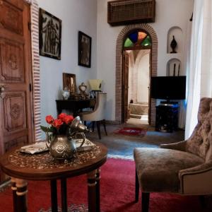 a living room with a table with a vase of flowers on it at Riad Les Trois Palmiers El Bacha in Marrakech