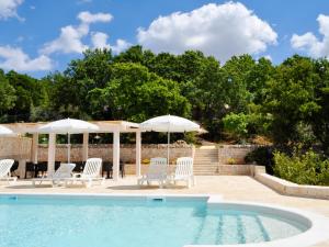 a swimming pool with white chairs and umbrellas at B&B Lamie Di Olimpia in Locorotondo