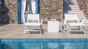 two chairs sitting next to a swimming pool at Mykonos Panormos Villas in Mykonos