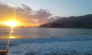 a sunset on the beach with the sun setting at Buljarica Bay Apartments in Petrovac na Moru