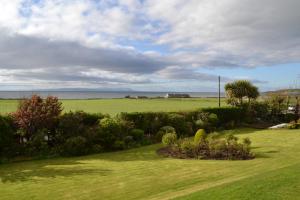a garden with a view of a field and the ocean at Burnside Farm B & B in Girvan +10 photos