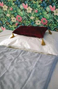 a white pillow on a bed with a floral wall at Blumen Apartment in Budapest