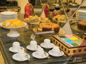 a buffet with cakes and other desserts on a table at Hotel Jacques Georges Business in Pelotas