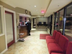 a lobby with red chairs and a counter in a building at North Vancouver Hotel in North Vancouver