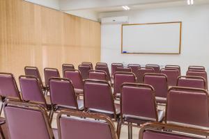 an empty lecture room with purple chairs and a whiteboard at Harbor Inn Jaraguá in Jaraguá do Sul