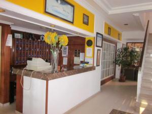 a lobby with a counter with a vase of yellow flowers at Hotel Sixto in Montalvo
