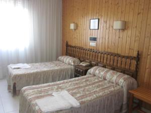 a hotel room with three beds and a window at Hotel Sixto in Montalvo