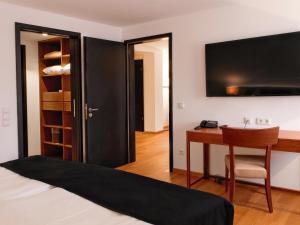 a bedroom with a bed and a desk and a tv at DORMERO Hotel Kelheim in Kelheim