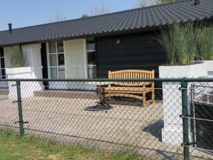 a fence with a bench in front of a house at De Turfstaeker in Ospel