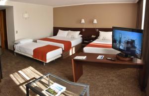 Habitación de hotel con 2 camas y TV de pantalla plana. en Hotel Director Vitacura, en Santiago