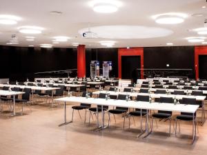 Cette grande chambre comprend des tables et des chaises blanches. dans l'établissement DORMERO Hotel Kelheim, à Kelheim