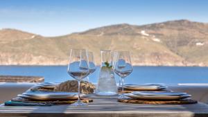 a table with wine glasses and plates and a view of the ocean at Mykonos Panormos Villas in Mykonos