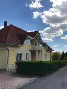 a yellow house with a brown roof on a street at Esther Apartman in Gyenesdiás